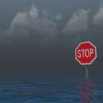 Stopp-Schild bei Hochwasser bei düsterem Wetter